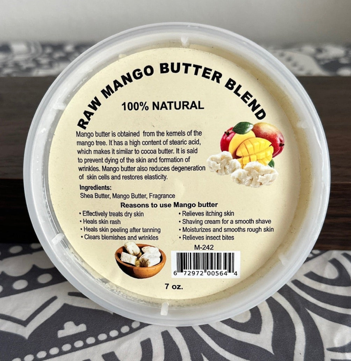 Container of raw mango butter blend on a patterned surface